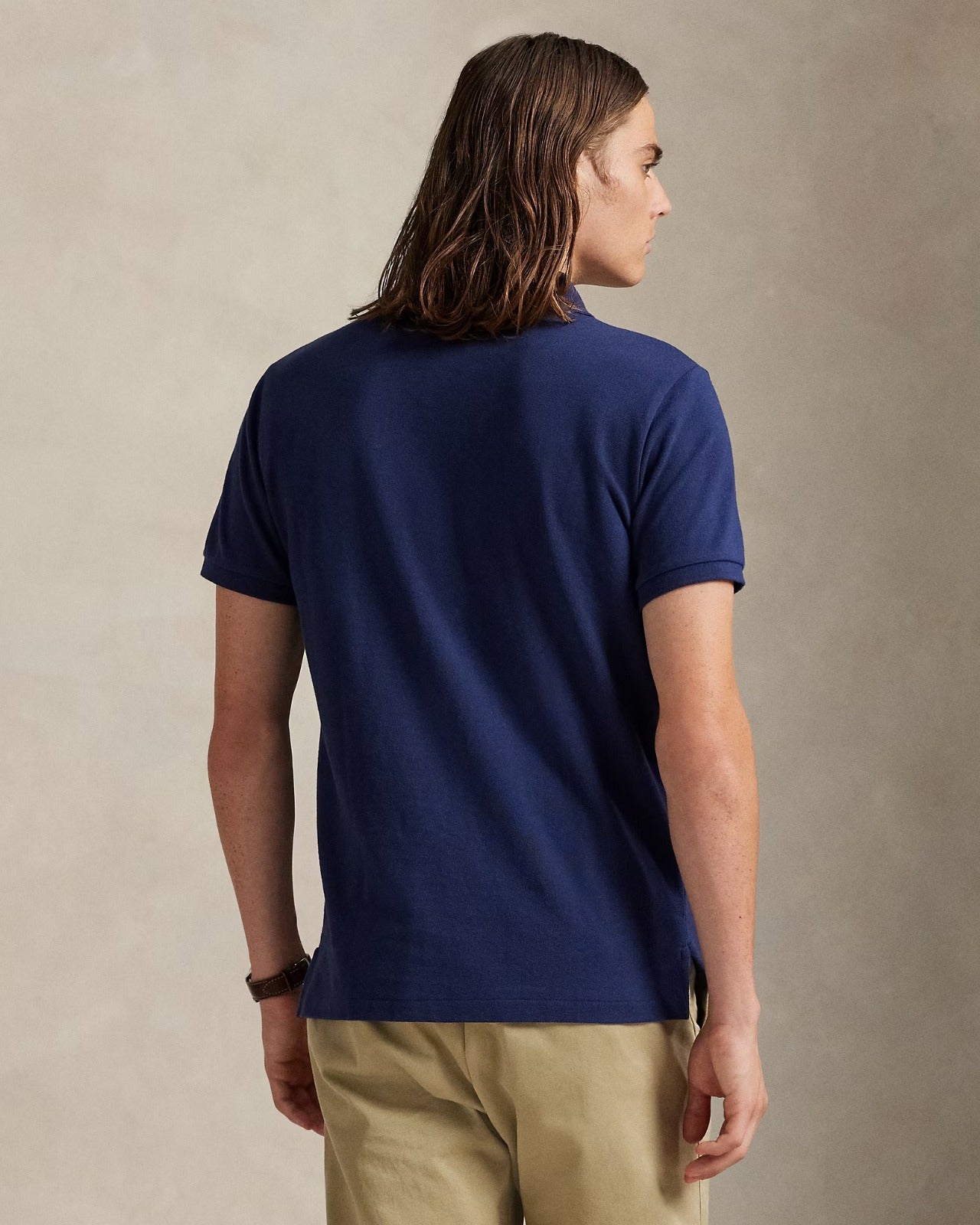 Back view of a man wearing a navy classic fit polo shirt by Ralph Lauren.
