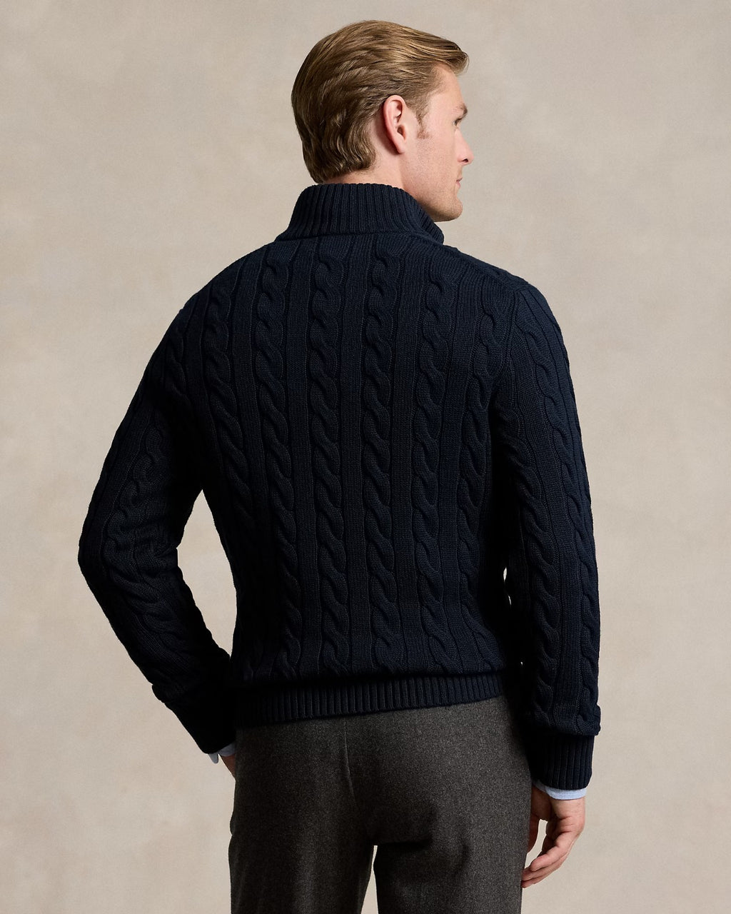 Back view of a male model wearing a cable-knit quarter-zip sweater in dark navy, showcasing its textured design.